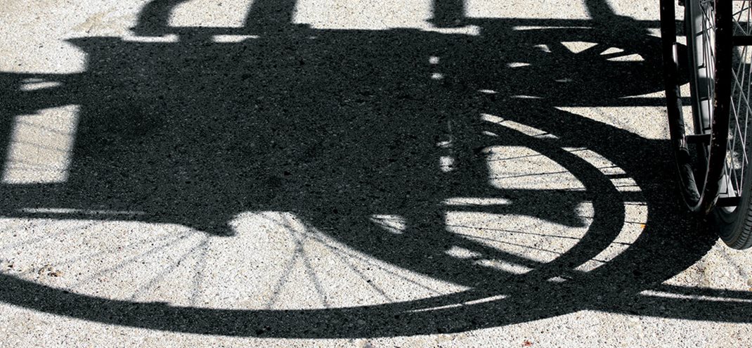 Schaduw van een rolstoel op de grond.