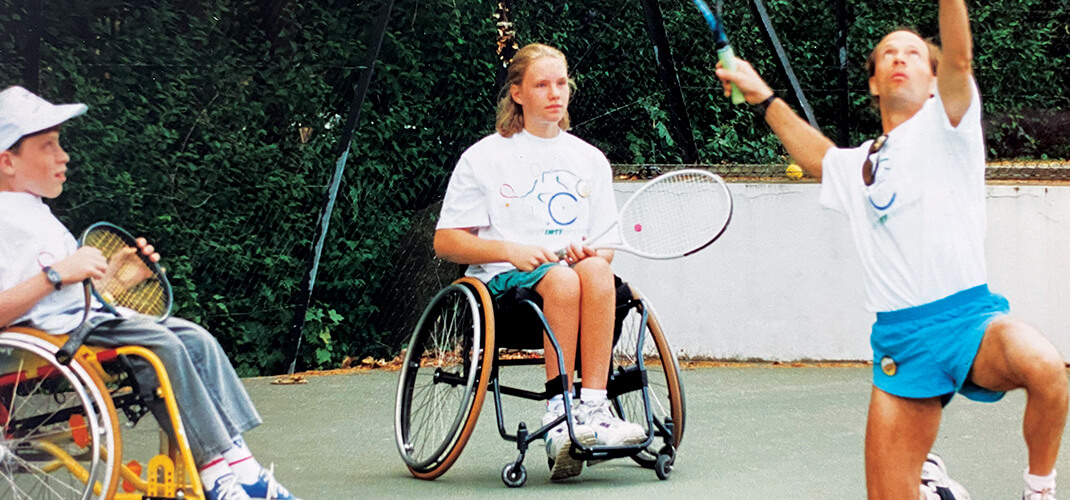 Een jonge Esther Vergeer die les krijgt in (rolstoel)tennis.