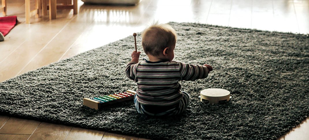 Een peuter die geluid aan het maken is met zijn muziekspeelgoed.