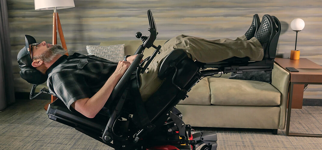 Een man gebruikt spraakbediening om zijn elektrische zitpositie in zijn rolstoel aan te passen.